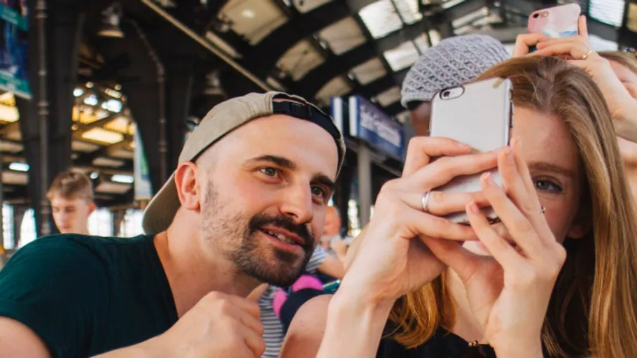 Gruppierung von Menschen macht ein Selfie an einem Bahnhof.